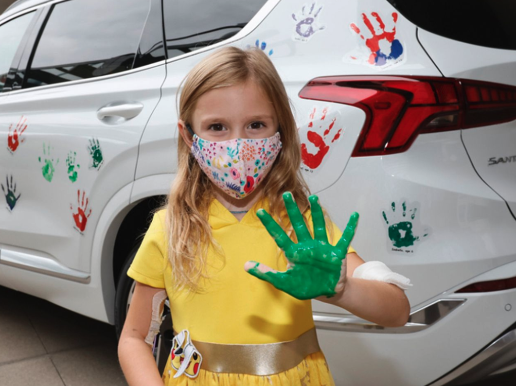 Young girl with a green painted hand participating in Hyundai Hope On Wheels event